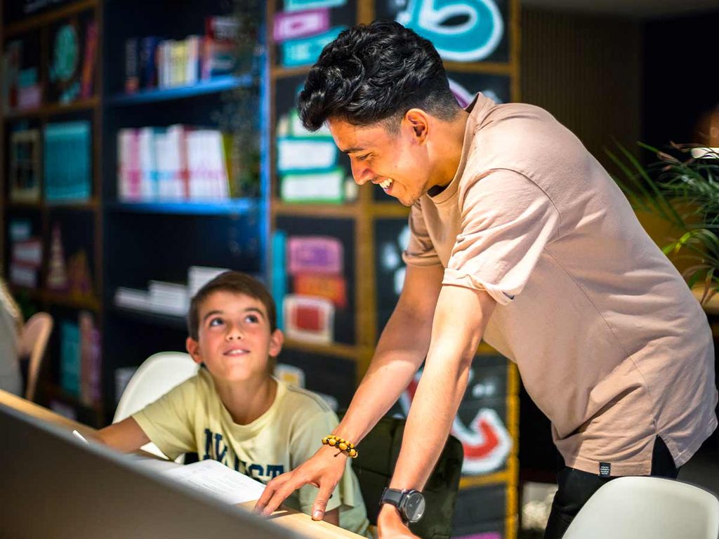 Kind krijgt persoonlijke ondersteuning bij het maken van schoolwerk.